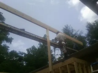 Carpenter setting a ridge beam over a new addition frame — Ice Dam Removal by Roofing Brothers in Mc Donald
