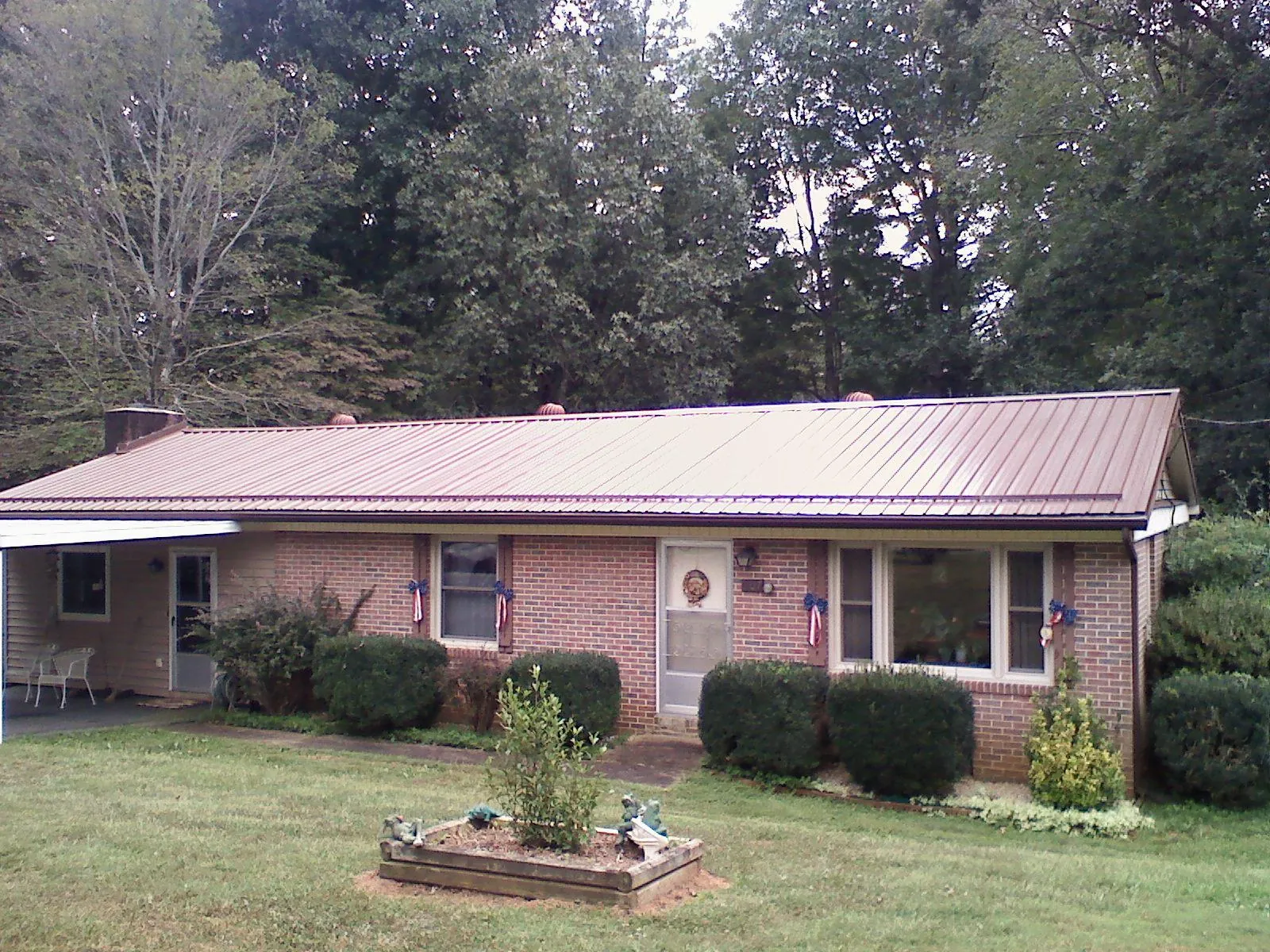 Bronze metal roof on a brick ranch home with a carport in Mc Donald