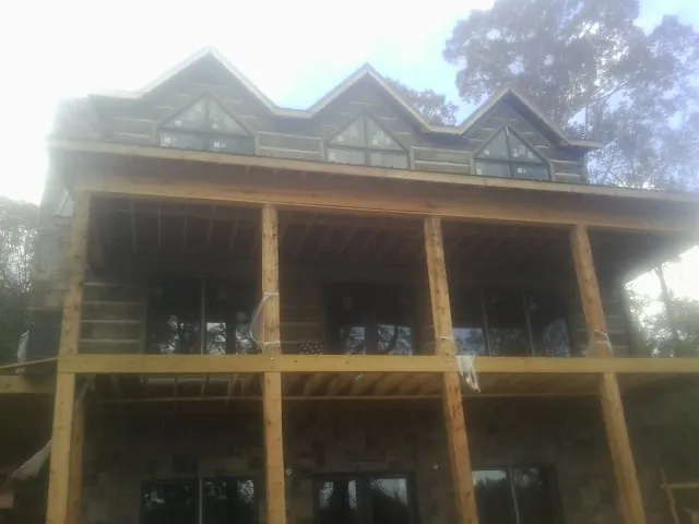 Dormers and porch framing on a large log home under construction — Roof Coating work by our crew in Mc Donald
